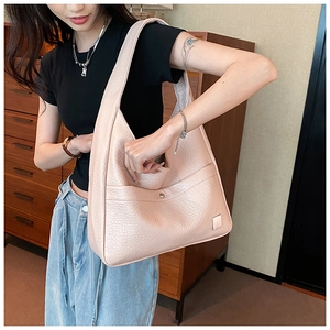Detail of pink lychee leather shoulder bag with metallic snap button and soft texture