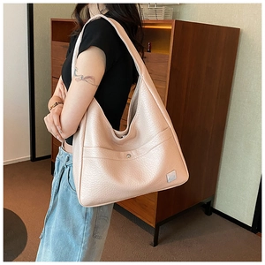 Detail of light pink pebbled leather hobo tote showing silver metal buckle and front pocket
