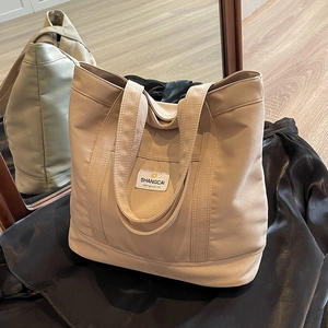 Minimalist beige canvas tote bag with outer pocket for women, versatile commuting shoulder bag