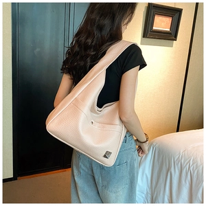 Detail of lychee textured leather and silver logo plate on beige hobo shoulder bag