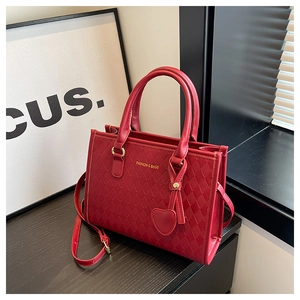 Détail du sac cabas en cuir matelassé rouge avec logo doré et breloque cœur