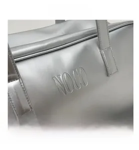 Macro detail of silver faux leather travel bag featuring embossed NOCO logo and handles