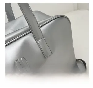 Close-up of the NOCO logo and refined stitching on a silver matte travel tote bag