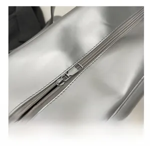 Close-up of the smooth metal zipper and premium leather texture on the silver travel bag