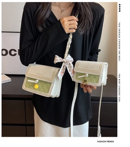 Dettaglio borsa a tracolla intrecciata bianca e verde con fiocco in seta e catena