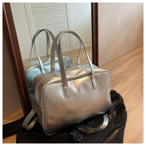 Detail of silver metallic Boston bag with embossed logo and adjustable shoulder strap