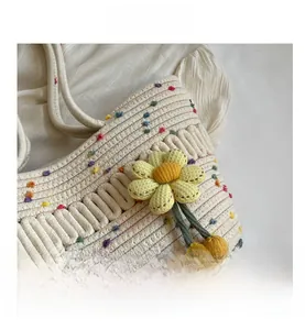 Close-up of woven straw tote bag with colorful dots and a 3D yellow sunflower pendant