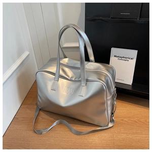 Detail of silver metallic travel bag with embossed NOCO logo and adjustable shoulder strap