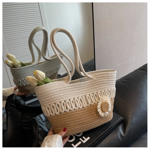 Detail of woven tote bag with bicolor wave texture and small daisy pendant accessory