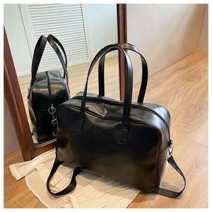 Detail of black faux leather travel bag with embossed letters and adjustable strap