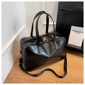 Detail of matte black tote bag with embossed MOCO logo and wide adjustable shoulder strap