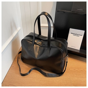 Detail of the black leather travel bag showing the embossed logo and adjustable shoulder strap