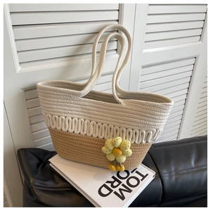 Detailed close-up of woven tote bag texture featuring a yellow knit flower accessory