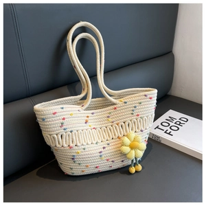 Detail of woven tote bag with colorful pom-poms and yellow sunflower charm accessory