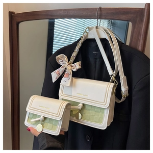 Dettaglio borsa a tracolla due pezzi crema e verde con fiocco e logo dorato elegante