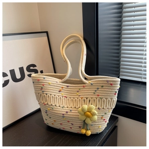 Detail of woven tote bag with colorful pom-poms and yellow crochet sunflower charm