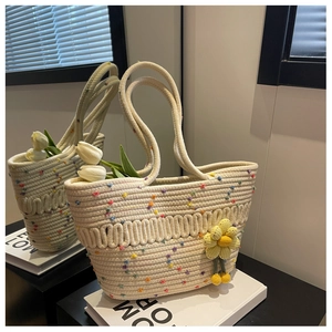 Detail of cream woven tote bag featuring rainbow accents and yellow crochet floral charm