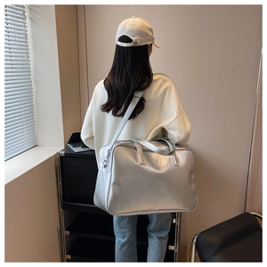 Silver large capacity travel bag with NOCO logo shown on model's shoulder for scale