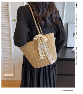Detail of hand-woven straw shoulder bag with elegant cream lace bow and slim cord strap