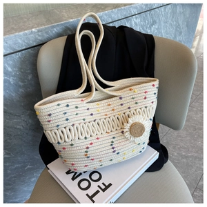 Close-up of woven tote bag featuring colorful dots and a large knitted daisy flower