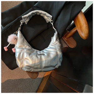 Detail van zilveren gewatteerde hobo-tas met een speelse roze pluche hanger op de achterkant