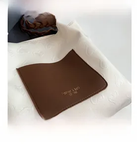 Detail of white canvas tote bag with heart texture and brown leather label decoration