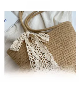 Detail showing the woven texture and white lace bow on the brown straw tote bag