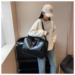 Detailed view of the black large-capacity leather travel bag worn by a model