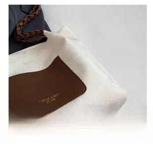 Detail of white faux leather tote with heart embossing and vintage leather patch