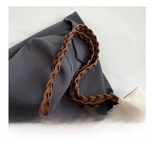 Detail of woven brown leather strap and heart embossed pattern on a white canvas tote bag
