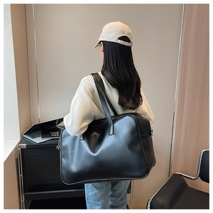 Side view of large black matte leather tote bag worn by a model in a modern office setting