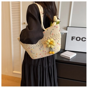 Detail of beige woven tote bag with colorful polka dots and a yellow knit flower charm