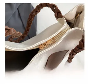 Detailed macro view of the smooth gold metal zipper and embossed texture on canvas tote