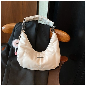 Detail van witte gewatteerde hobo tas op zwarte blazer met een roze pluche bedeltje