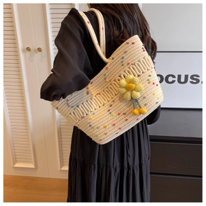 Detail of hand-woven tote bag with colorful fuzzy balls and sunflower charm accessory