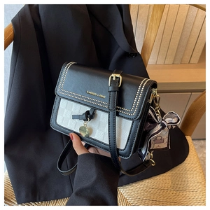 Dettaglio borsa a tracolla con borchie dorate, logo e accessorio foulard in seta alla moda