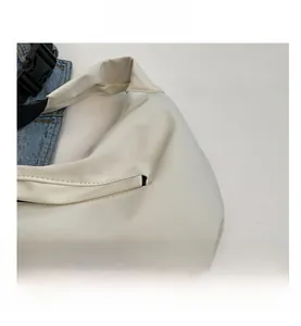 Vue détaillée de la texture du tissu en nylon beige doux et du zip d'un sac à bandoulière