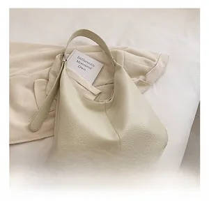 Close-up of pebble leather texture on minimalist cream hobo bag with wide strap