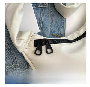 Détail d'un sac en nylon blanc avec double fermeture éclair noire et bandoulière