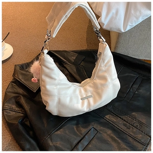 Detailopname van een witte gewatteerde handtas met roze pompon op een leren jasje