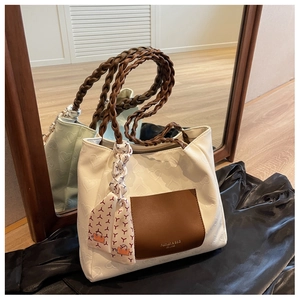 Detail of white heart-embossed tote bag with brown woven handles and silk scarf accent