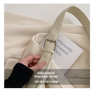 Detail of adjustable strap and silver buckle on off-white pebbled leather bucket bag