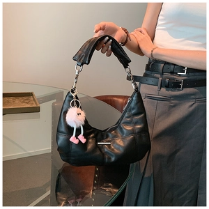 Detail van zwarte gewatteerde hobo tas met een stijlvolle pluche hanger eraan
