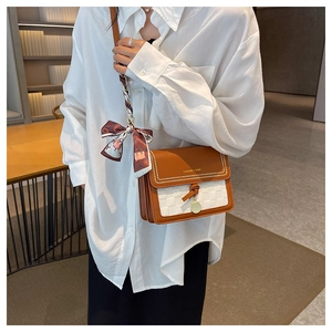 Dettaglio della borsa a tracolla in pelle marrone con motivo a quadri e foulard
