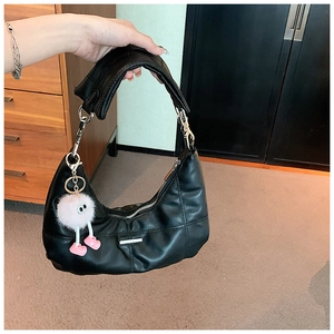 Detail van de zwarte gewatteerde hobo-tas met zilveren rand en roze pluche pop-hanger