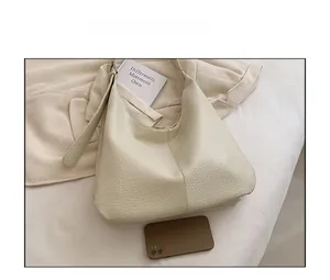 Detail of cream leather hobo bag with pebble texture and mobile phone for size reference