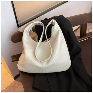 Close-up of cream leather tote bag with lychee texture on a vintage wood chair