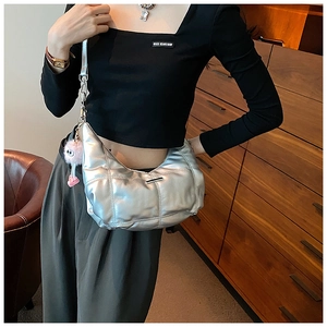 Detail van zilveren gewatteerde hobo-tas met roze pluche hanger en metalen textuur