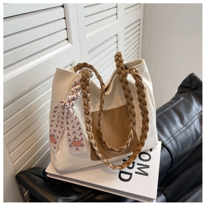 Detail of cream canvas tote bag with heart embossing and woven handles with silk scarf