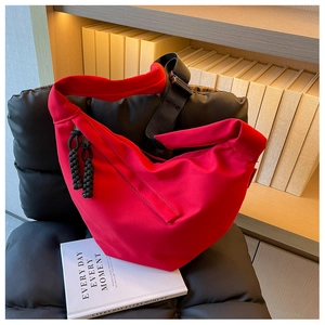 Détail d'un sac demi-lune en nylon rouge avec nœud en corde noire et bandoulière large